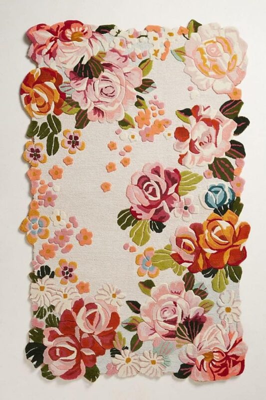 Hand tufted irregular floral rug with vintage roses, daisies, and scalloped border in pink, red, and pastel tones