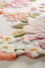 Hand tufted irregular floral rug with vintage roses, daisies, and scalloped border in pink, red, and pastel tones